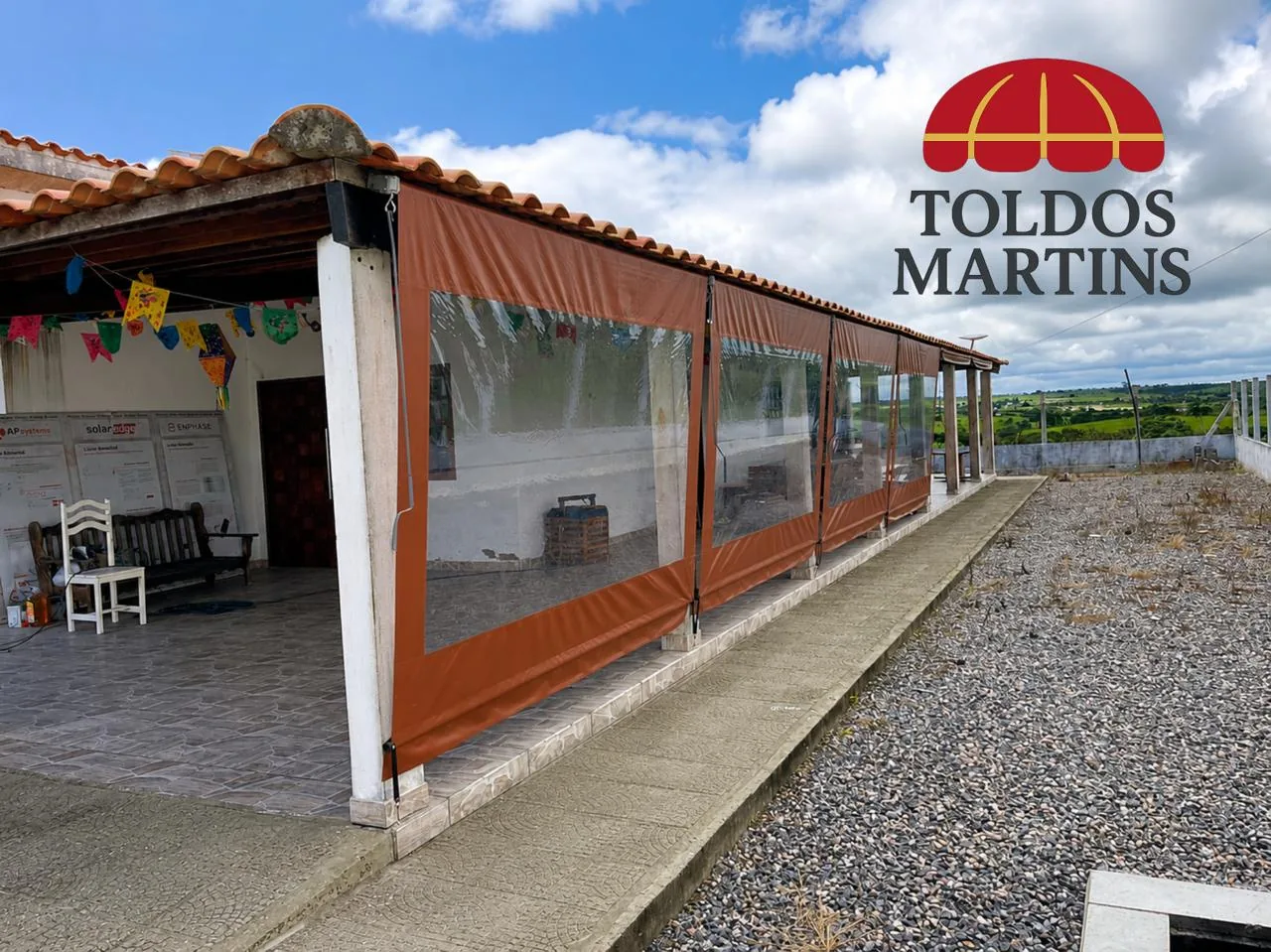 Toldo cortina vertical laranja com visor cristal fechando varanda de casa em Rio Pomba